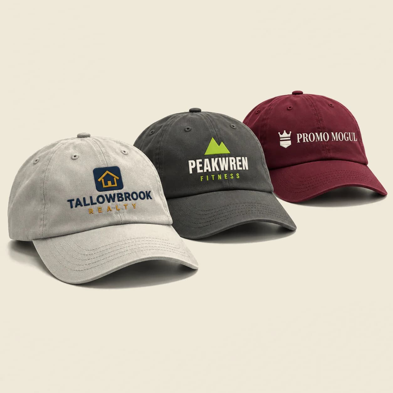 Custom Embroidered Dad Hats: Light gray, dark gray and burgundy dad hats with embroidered logos, sample artwork for a fictional brand and the PromoMogul logo